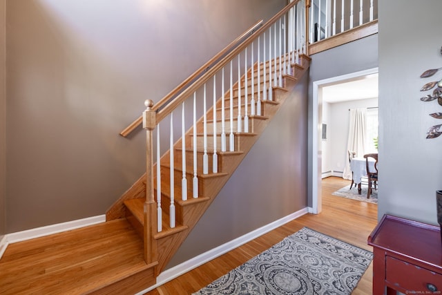 staircase featuring baseboards, wood finished floors, and a baseboard radiator