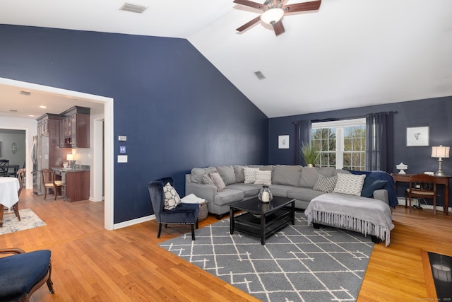 living room featuring visible vents, a ceiling fan, light wood-style floors, and a baseboard heating unit