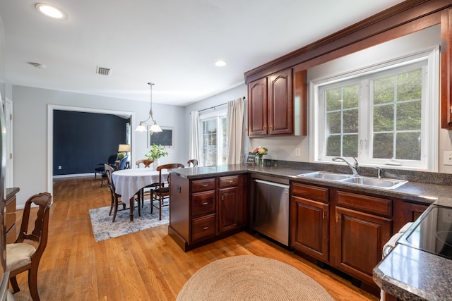 kitchen with stainless steel dishwasher, a sink, a healthy amount of sunlight, and dark countertops
