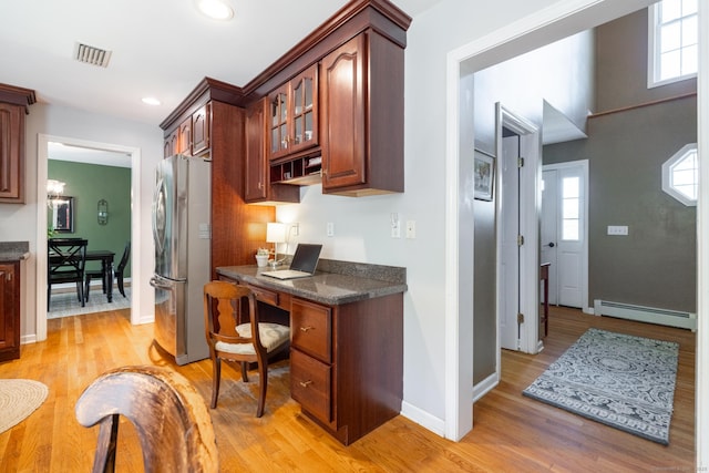kitchen with freestanding refrigerator, glass insert cabinets, baseboard heating, and light wood-style flooring