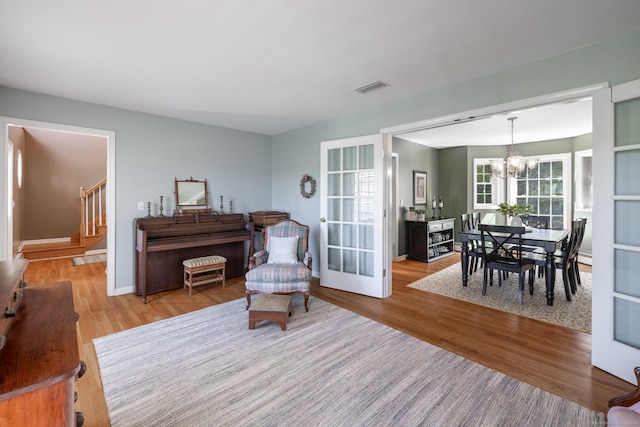 living room featuring stairs, an inviting chandelier, wood finished floors, and visible vents
