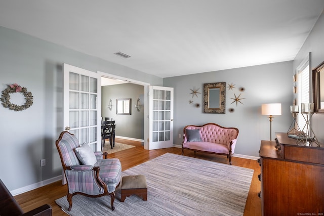 living area featuring french doors, baseboards, wood finished floors, and visible vents