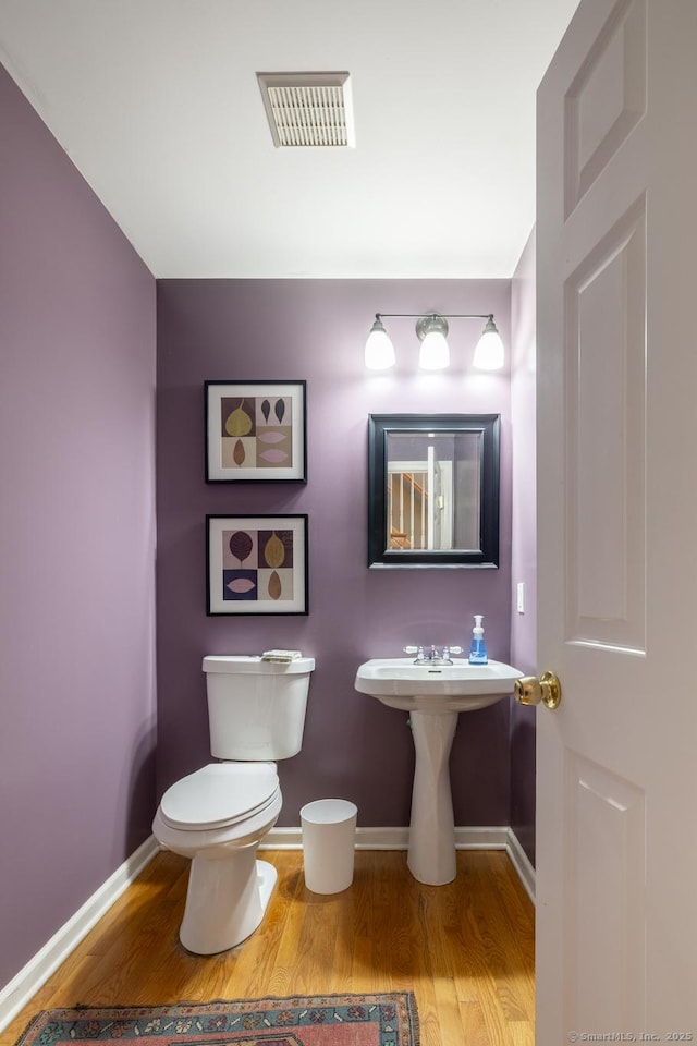 bathroom with toilet, baseboards, visible vents, and wood finished floors