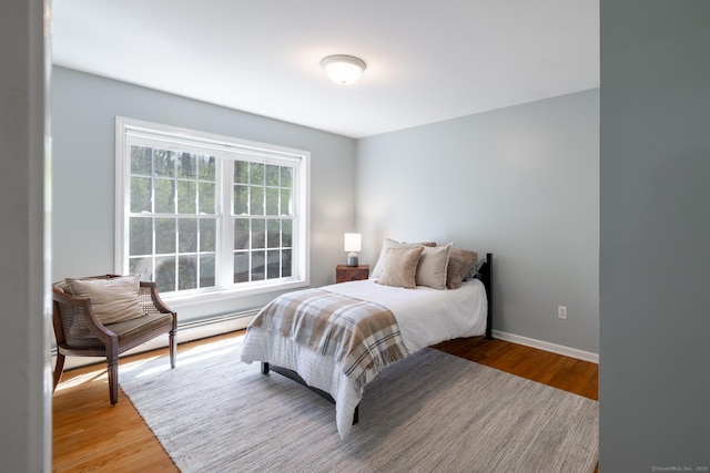 bedroom with baseboards, light wood-style flooring, and a baseboard radiator