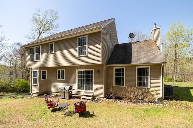 back of house with a lawn, a chimney, and central AC