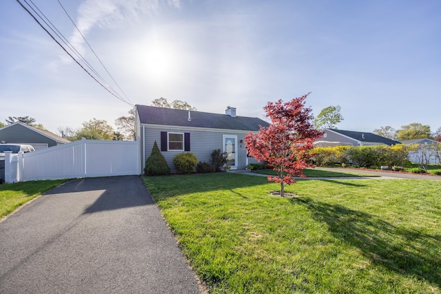 view of front of home with fence, a chimney, and a front lawn