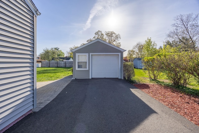 detached garage with aphalt driveway and fence