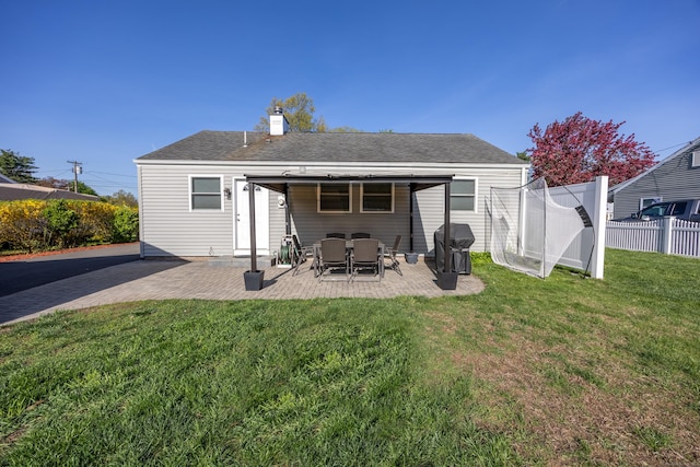 rear view of house featuring fence, a chimney, a lawn, and a patio area