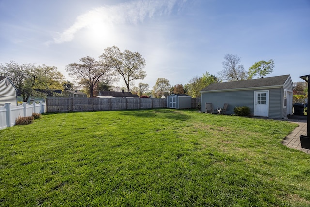 view of yard with an outdoor structure, a fenced backyard, and a shed