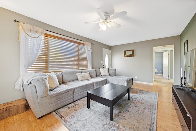 living room featuring baseboards, a ceiling fan, and light wood-type flooring