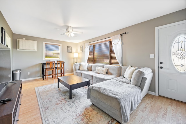 living room featuring light wood-style floors, a ceiling fan, and baseboards