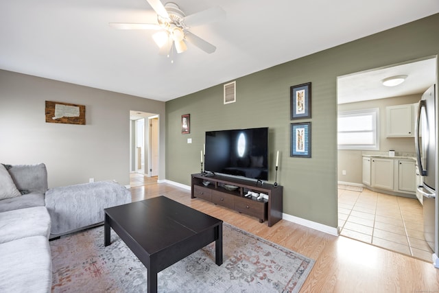 living area with light wood-style floors, baseboards, a ceiling fan, and visible vents