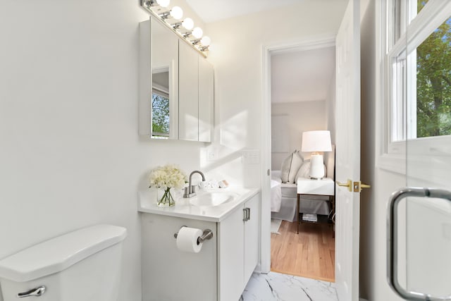 ensuite bathroom featuring vanity, ensuite bathroom, toilet, and marble finish floor