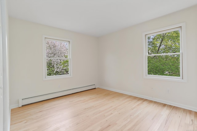spare room featuring baseboards, a wealth of natural light, baseboard heating, and wood finished floors