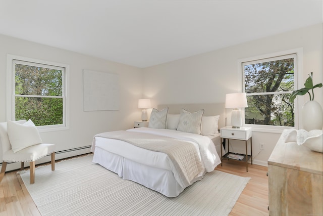 bedroom with light wood-type flooring, baseboard heating, and multiple windows