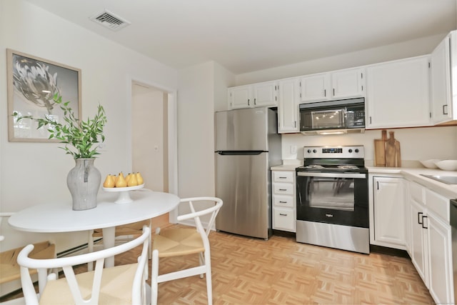 kitchen with visible vents, appliances with stainless steel finishes, light countertops, a sink, and white cabinetry
