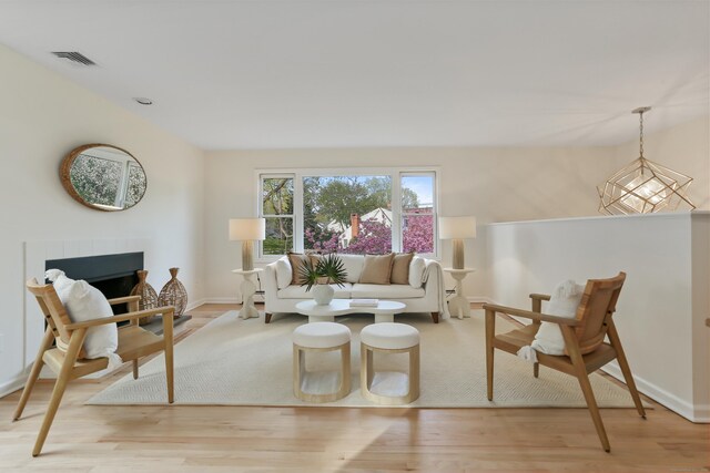living area with baseboards, visible vents, light wood-type flooring, and a tile fireplace