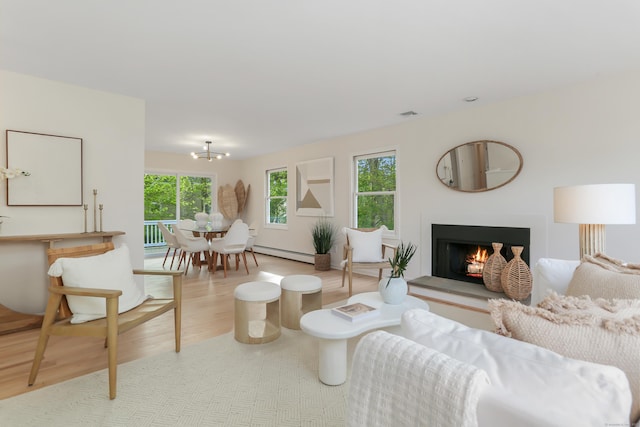 living room featuring baseboard heating, visible vents, a chandelier, wood finished floors, and a lit fireplace