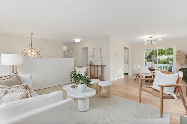 living area with an inviting chandelier, baseboards, and light wood-style floors