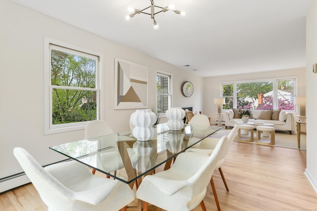 dining space with a chandelier, baseboard heating, and light wood-type flooring