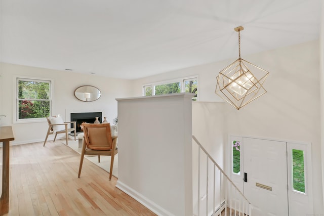 interior space with a healthy amount of sunlight, baseboards, light wood finished floors, and a notable chandelier