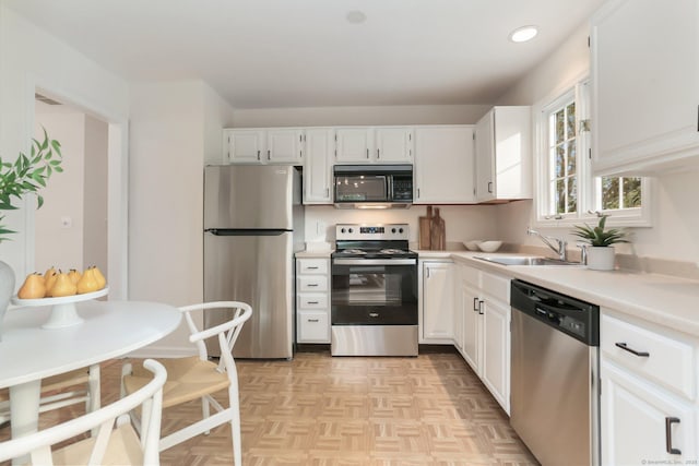 kitchen with a sink, light countertops, white cabinets, stainless steel appliances, and recessed lighting