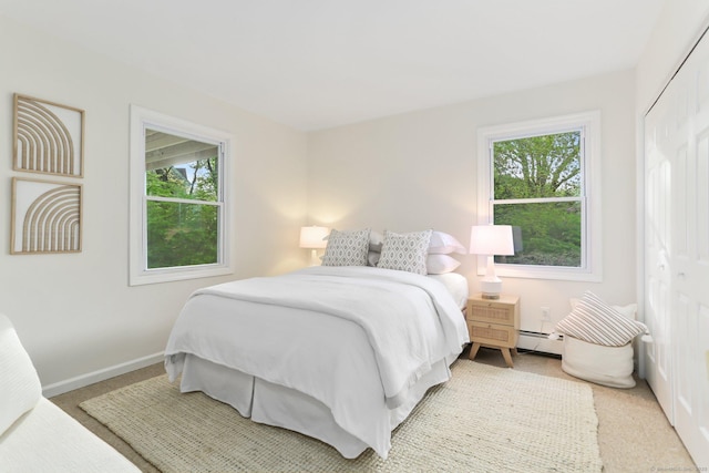 bedroom with baseboards, a baseboard heating unit, and multiple windows