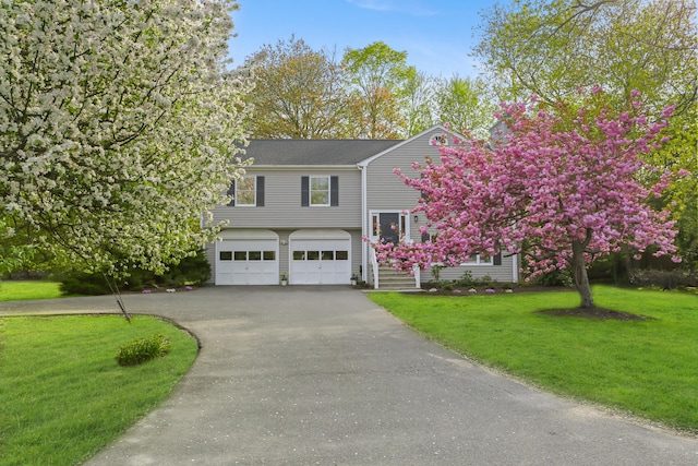 view of front of property featuring an attached garage, a front yard, and aphalt driveway