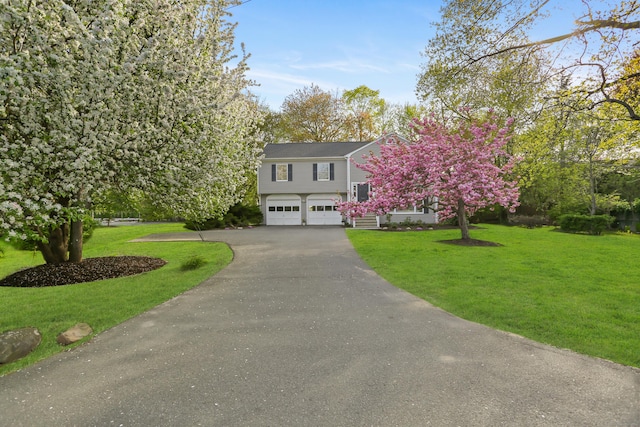 view of front of house with an attached garage, driveway, and a front lawn