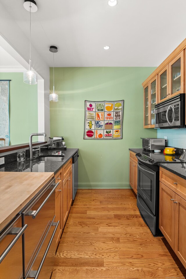 33 Hale Ln Unit 33, Darien, CT 06820 - kitchen featuring a sink, light wood finished floors, stainless steel appliances, pendant lighting, and glass insert cabinets