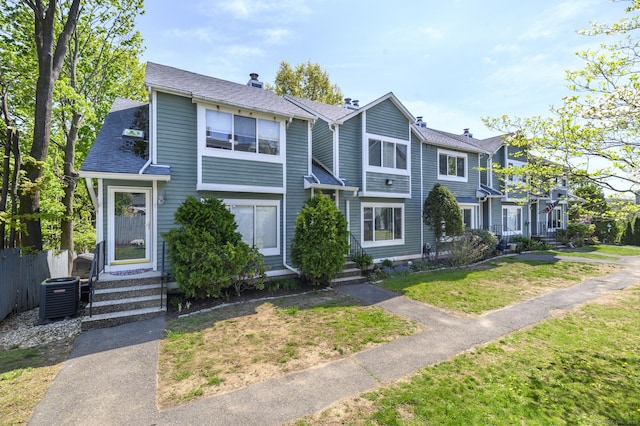 multi unit property with a chimney, central air condition unit, a shingled roof, and a front lawn