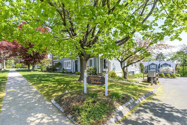 view of property hidden behind natural elements with a front lawn and a residential view