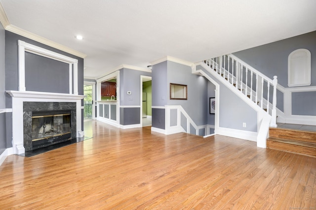 unfurnished living room featuring a premium fireplace, light wood-type flooring, stairway, baseboards, and recessed lighting