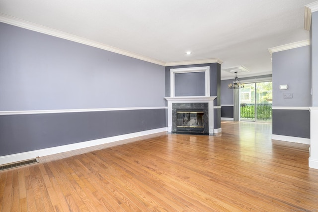 unfurnished living room featuring an inviting chandelier, a fireplace, crown molding, visible vents, and baseboards