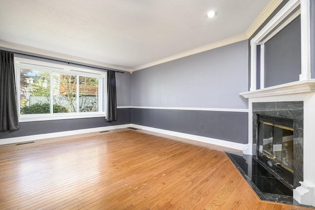 unfurnished living room with ornamental molding, baseboards, a high end fireplace, and wood finished floors