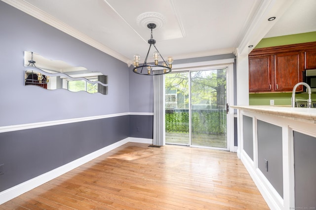unfurnished dining area with plenty of natural light, a chandelier, ornamental molding, and light wood-style floors