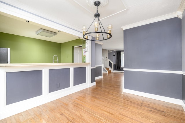interior space with baseboards, a notable chandelier, ornamental molding, and wood finished floors
