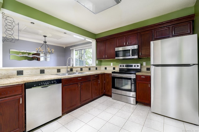 kitchen with a sink, ornamental molding, a chandelier, light countertops, and appliances with stainless steel finishes