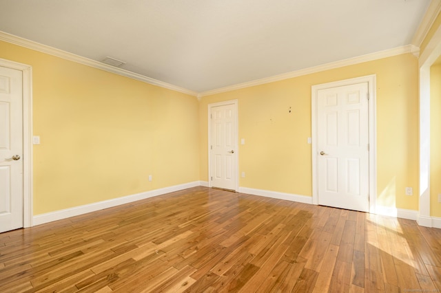 spare room featuring crown molding, light wood-style flooring, and baseboards