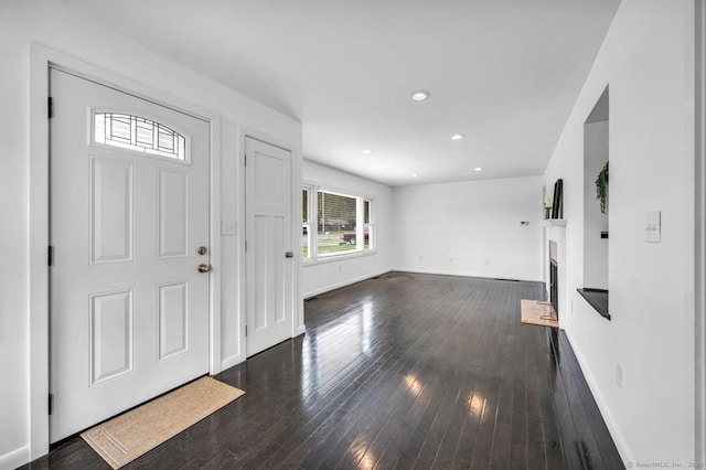 foyer entrance with baseboards, a fireplace, recessed lighting, and dark wood-type flooring