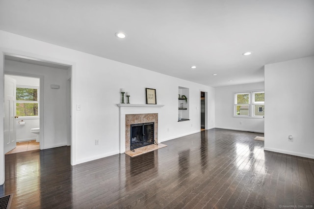 unfurnished living room featuring a tiled fireplace, baseboards, recessed lighting, and wood finished floors