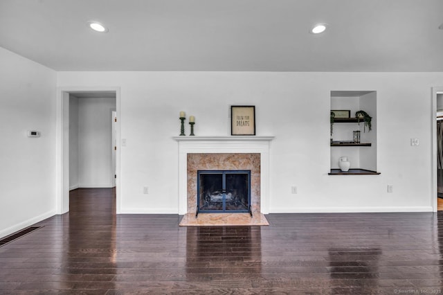 unfurnished living room featuring a high end fireplace, baseboards, hardwood / wood-style flooring, and visible vents