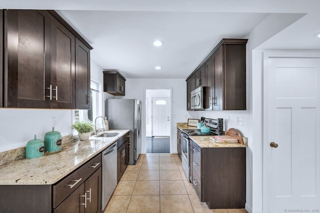 kitchen with appliances with stainless steel finishes, dark brown cabinets, a sink, light stone counters, and recessed lighting