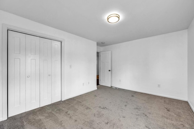 unfurnished bedroom featuring carpet floors, baseboards, and a closet