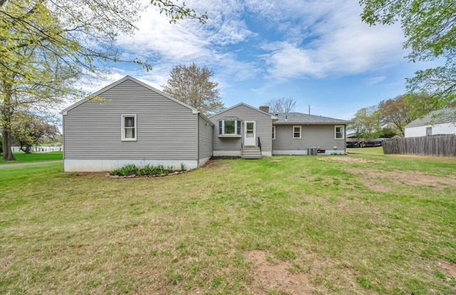 back of property featuring a lawn, fence, a chimney, and cooling unit