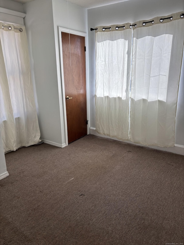 empty room featuring carpet and baseboards
