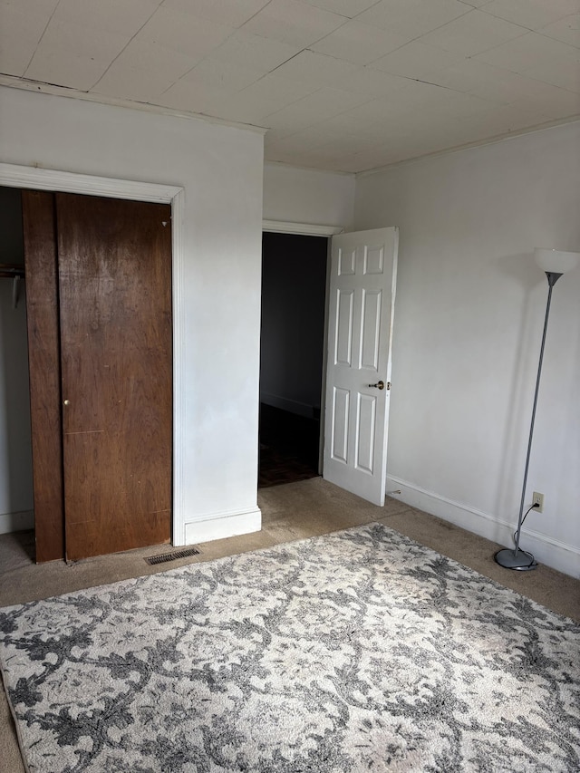 unfurnished bedroom featuring baseboards, visible vents, a closet, and carpet