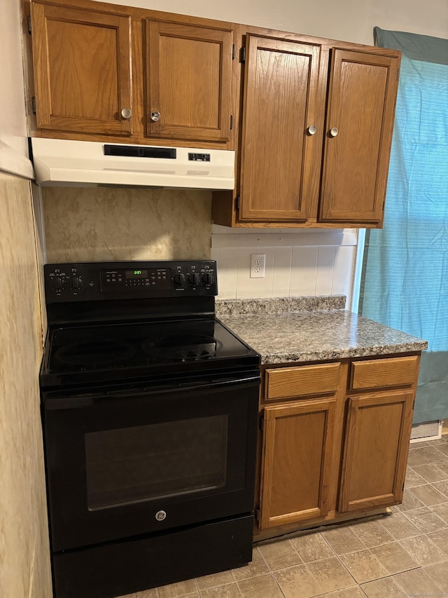 kitchen with tasteful backsplash, electric range, under cabinet range hood, and brown cabinets