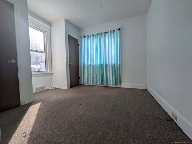 spare room with carpet flooring, visible vents, and baseboards