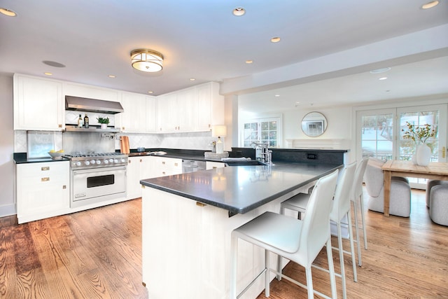 53 Sylvan Rd N, Westport, CT 06880 - kitchen with stainless steel appliances, dark countertops, a sink, white cabinets, and light wood-type flooring